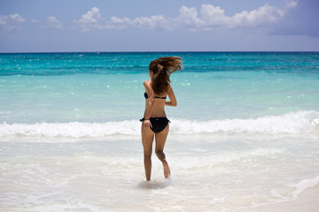 Fototapeta na wymiar Junge sportliche Frau rennt in das Karibische Meer