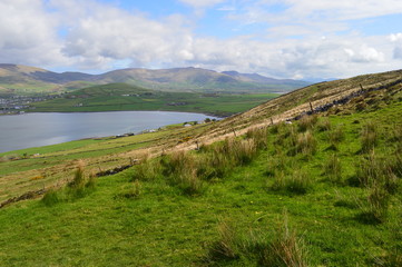 Obraz premium Typical Irish green landscape with hills in the background and lake