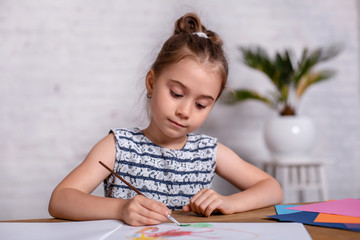 Inspired little girl at the table draw with paints
