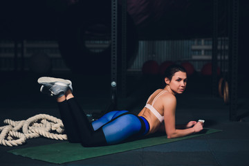 Fit young woman lying on exercise mat doing stomach exercises.