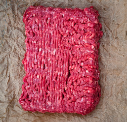Block of minced beef meat on wrinkled brown wax paper