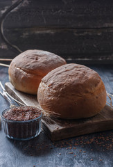 Homemade  freshly baked  bread with flax seeds  on dark wooden background