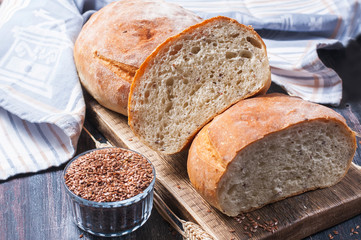 Homemade  freshly baked  bread with flax seeds  on dark wooden b