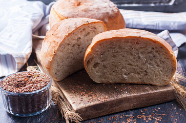 Homemade  freshly baked  bread with flax seeds  on dark wooden b
