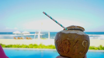 Coconut with straw with 2019 drawing on the beach near the sea with New year winter holiday concept