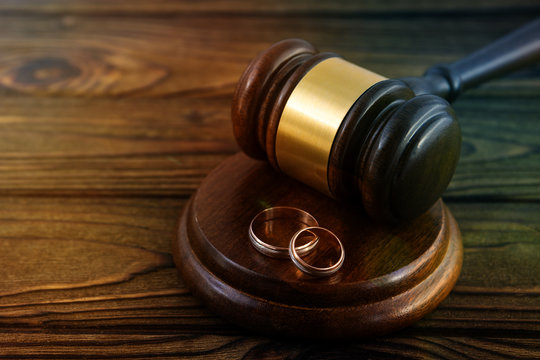 judge's hammer, a pair of gold engagement rings on wooden background. family law