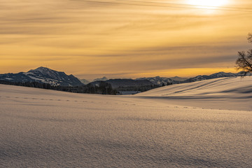Fototapeta na wymiar Landschaft schneebdeckt mit Berggipfel im Hintergrund Abendrot