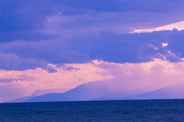 seascape of sunset purple sky with clouds and sea open water with mountains in background