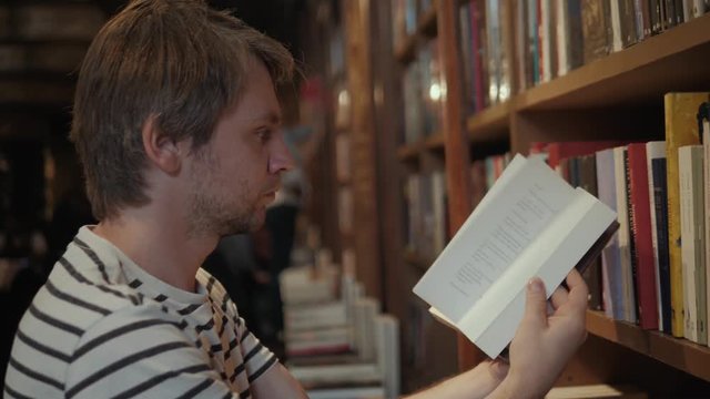 Handsome bearded student tourist man reading book in library store shop supermarket choose dictionary