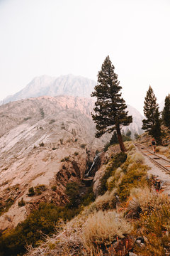Man walking on railroad tracks surrounded by mountains and trees