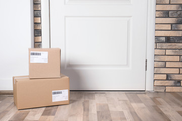 Cardboard parcel boxes on floor near apartment entrance. Mockup for design