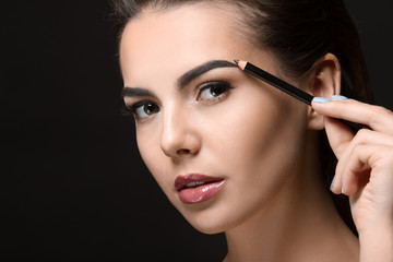 Young woman with beautiful eyebrows on black background