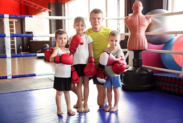 Little children with trainer in boxing ring