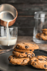 Plate with tasty chocolate chip cookies on wooden table