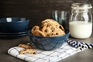 Bowl with tasty chocolate chip cookies on table