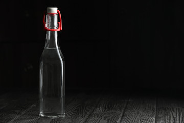 Fototapeta na wymiar Glass bottle with vinegar and space for text on black background