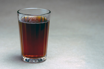 Glass with black tea on a brown background