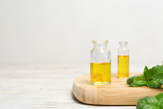 Wooden board with glass bottles of basil oil, leaves and space for text