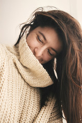 Portrait of young attractive woman with no makeup and gorgeous hair in knitted sweater smiling in...