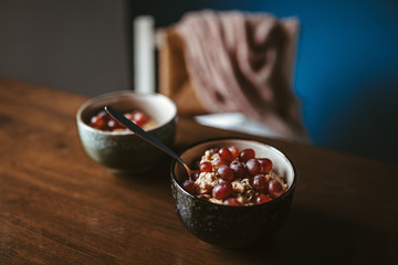 Zwei Schüsseln Porridge und Weintrauben auf einem Holztisch