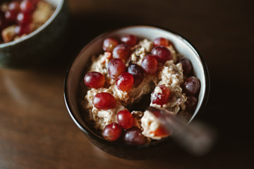 Zwei Schüsseln Porridge und Weintrauben auf einem Holztisch