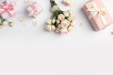 Flat lay composition with beautiful roses and gift boxes on white background. Space for text