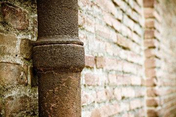 Detail of a downpipe against a brick wall - (Tuscany - Italy)