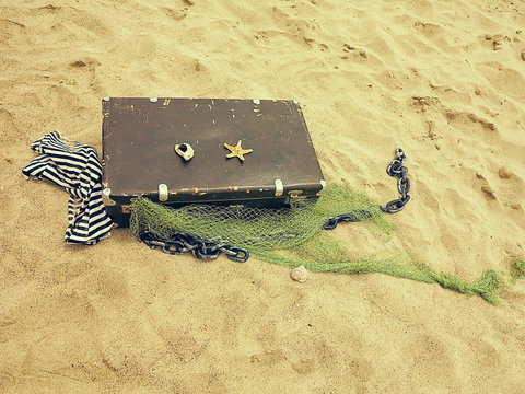 Old vintage suitcase for travel and family vacations lies on the beach. Sea shore  ocean. Photo in a trendy retro style