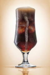 Crowded glass with cola and ice, light toning, close-up