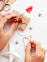 Woman wrapping Christmas and New Year DIY presents in craft paper. Gift tied with toy train as decoration.