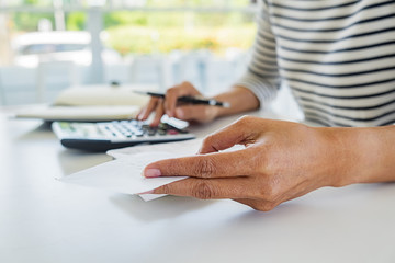 Woman with bills and calculator. Woman using calculator to calculate bills at the table in office. Calculation of costs.