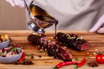 The cook waters venison meat with juniper sauce with nuts