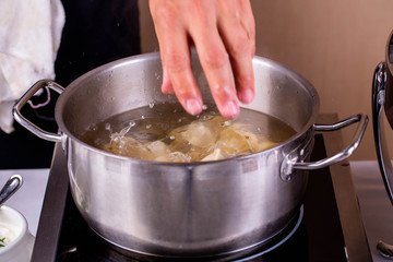 The boiling pelmeni in a pan with spices