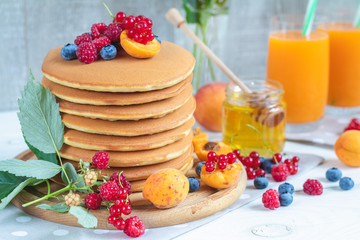 Fresh delicious pancakes with summer berries on light surface