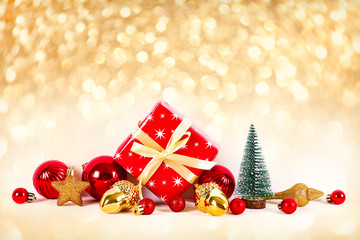 Minimalistic festive composition with small christmas tree, wrapped present and colorful matte balls. Fancy beautiful decoration for christmas pine tree. Background, copy space, close up, front view.