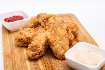 Fried breaded chicken wings on a wooden board.

