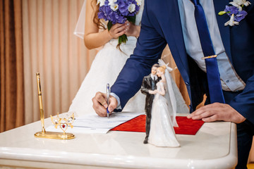 The groom signs the marriage registration documents. Young couple signing wedding documents