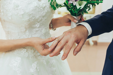 The bride wears a ring to the groom at the wedding ceremony