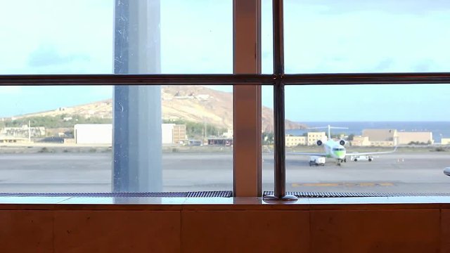 Man walking back and forth with carry on luggage at Las Palmas airport terminal. Airplane on landing area as passenger passes by. Travel, transportation concepts