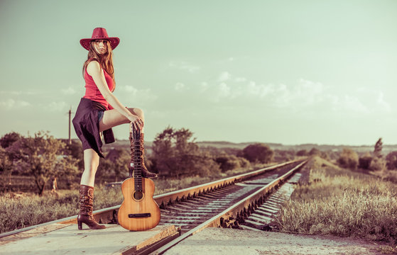 gourgeous young brunet with guitar at countryside railways