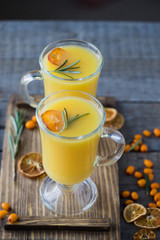 Orange hot lemonade from berries and tangerines in glasses. Dried slices of tangerines and oranges. Gray concrete background.
