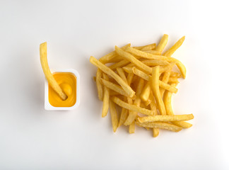 French fries on a white background. A pile of finished french fries close-up on a white background. Near the plastic container with cheese sauce.