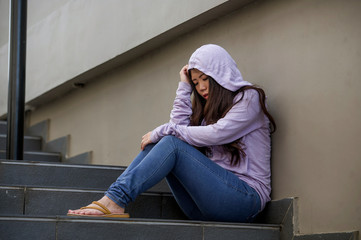 depressed Asian Chinese student woman or bullied teenager girl sitting outdoors on street staircase...