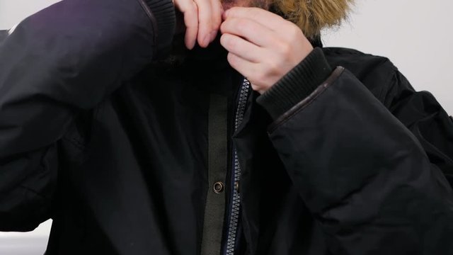 Handsome young man wearing a light winter parka jacket - smiling to the camera on isolated background zipper hood strong