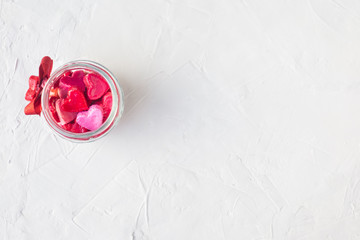 Valentine's day concept. jar with small hearts red and pink on a light background.