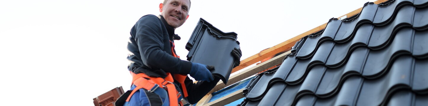 Banner frei f&uuml;r Dachdecker Handwerk Ausbildung am neuen Dachziegel Dach, Isolierter Dachdecker Bauarbeiter kann neues Dach mit schwarz gl&auml;nzenden Pfannen eindecken
