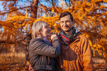 Adult son kissing his middle-aged mother in autumn park. Family values