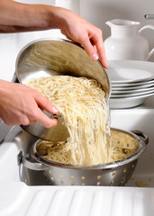 MAN DRAINING SPAGHETTI INTO COLLANDER