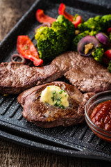 Grilled Beef steak with garlic butter and vegetables. Meat with grilled bell pepper, broccoli and onions.
