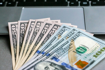 Closeup view of one hundred and fifty dollar banknotes lying on the laptop keyboard.